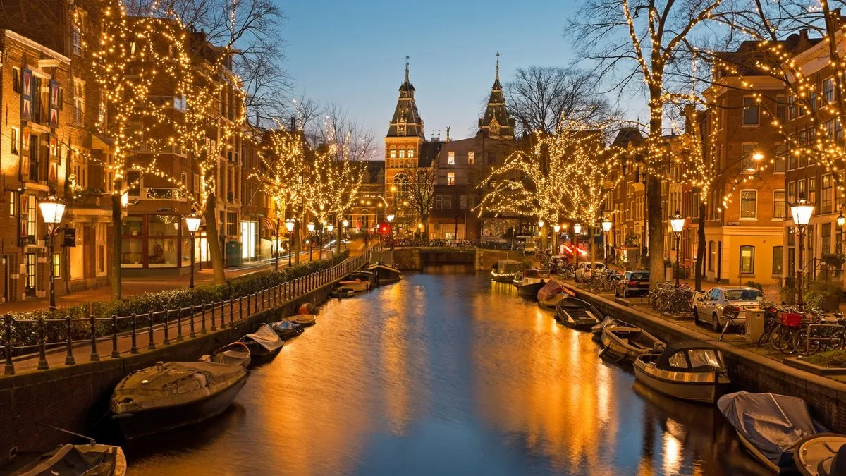 Amsterdam’da aydınlatmalı ağaçlarla çevrili kanal ve tekneler