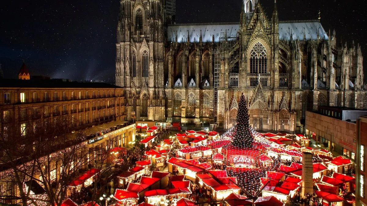 Köln Katedrali önünde kırmızı çatılı Noel pazarı tezgahları, gece